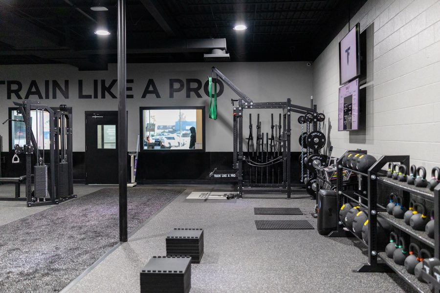The training floor with cable machines, plyo boxes and a kettlebell rack under the Train Like A Pro wall.