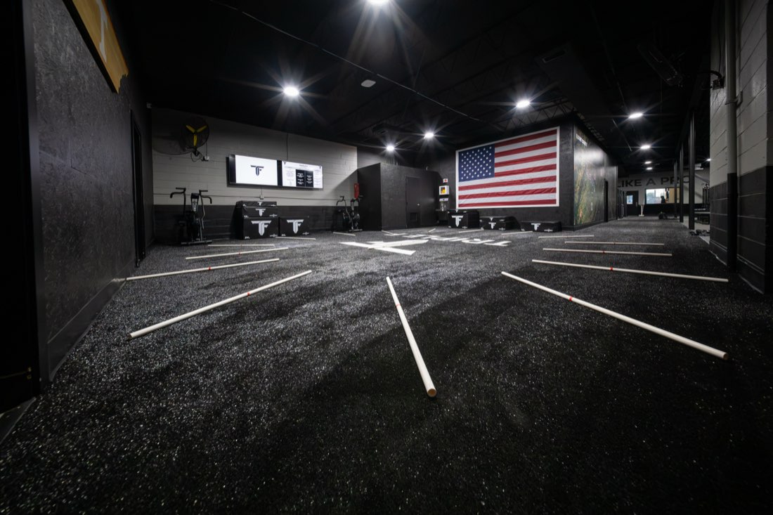 The turf sprint lanes at Triple F Blount County, with an American flag mural on the far wall.